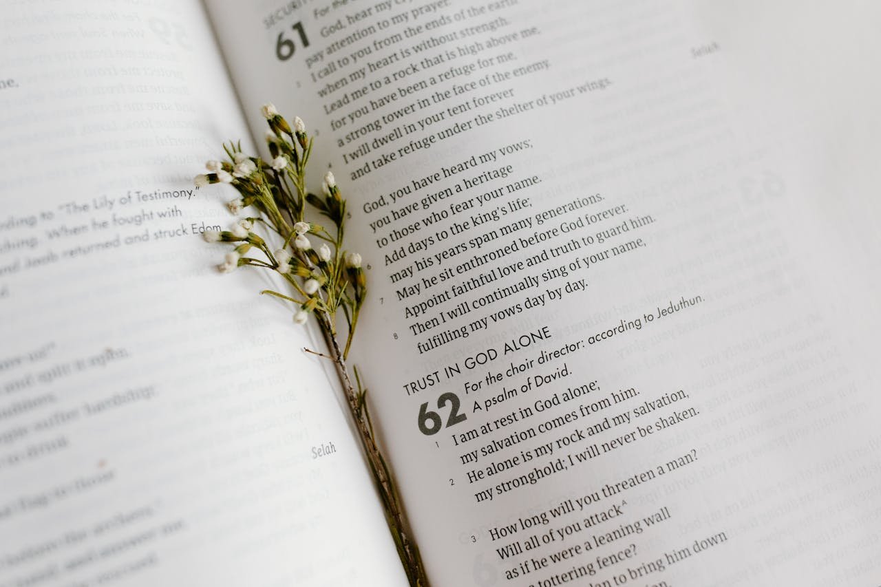 why-choose-us-01 A close-up of an open Bible page with scripture and delicate white flowers.