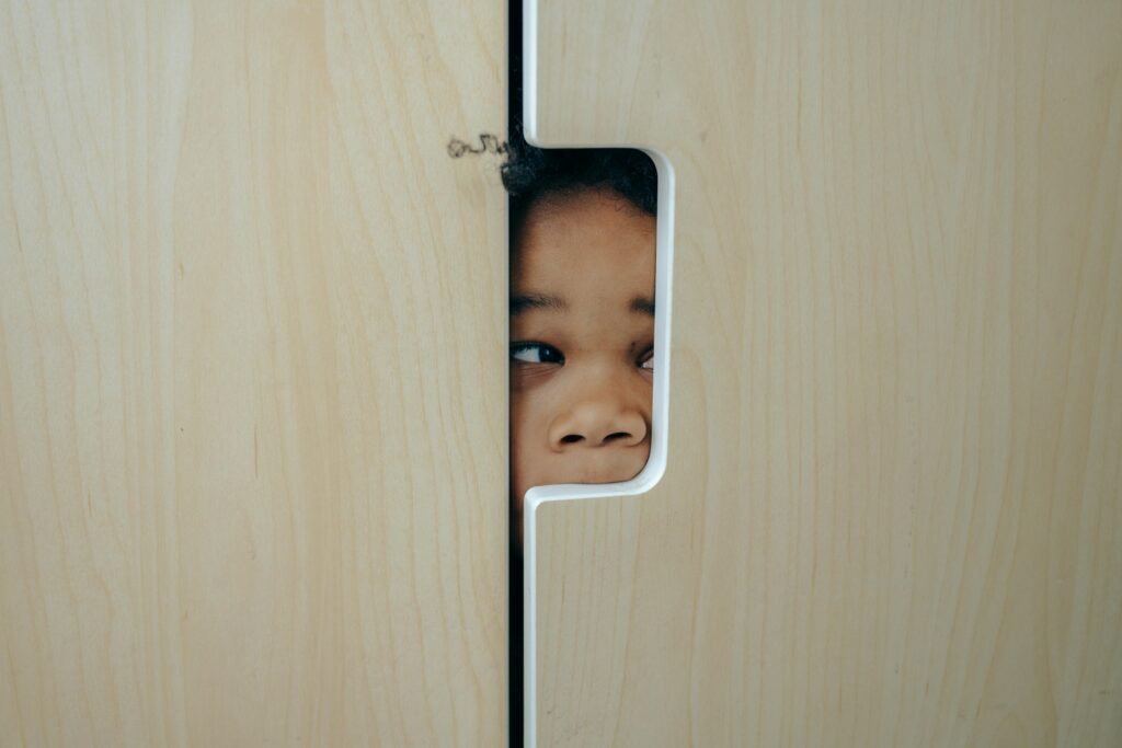 pexels-photo-4545972-4545972 Anonymous funny little ethnic child hiding in wardrobe and peeping through hole while playing at home