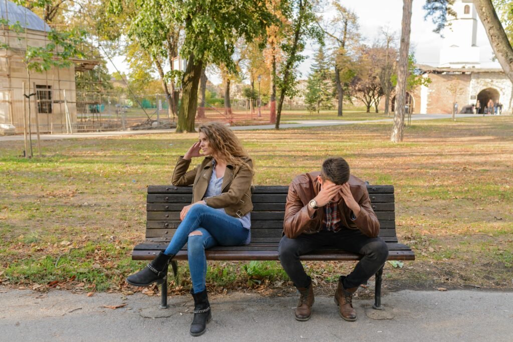 pexels-photo-984949-984949 An upset couple seated on a park bench, expressing frustration during an autumn day.