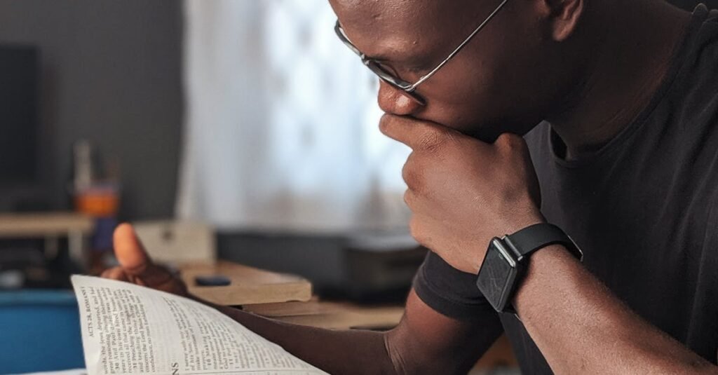 Young man deeply engaged in reading a book at home, fostering knowledge and wisdom.