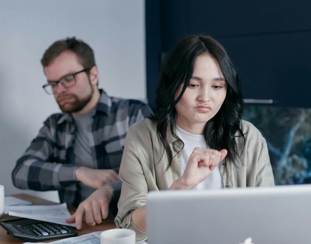Couple stressed over finances while working on a laptop and calculator at home.