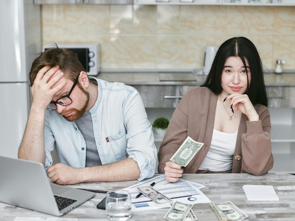 A couple managing their finances in a kitchen setting, showcasing money, debt, and budgeting challenges.