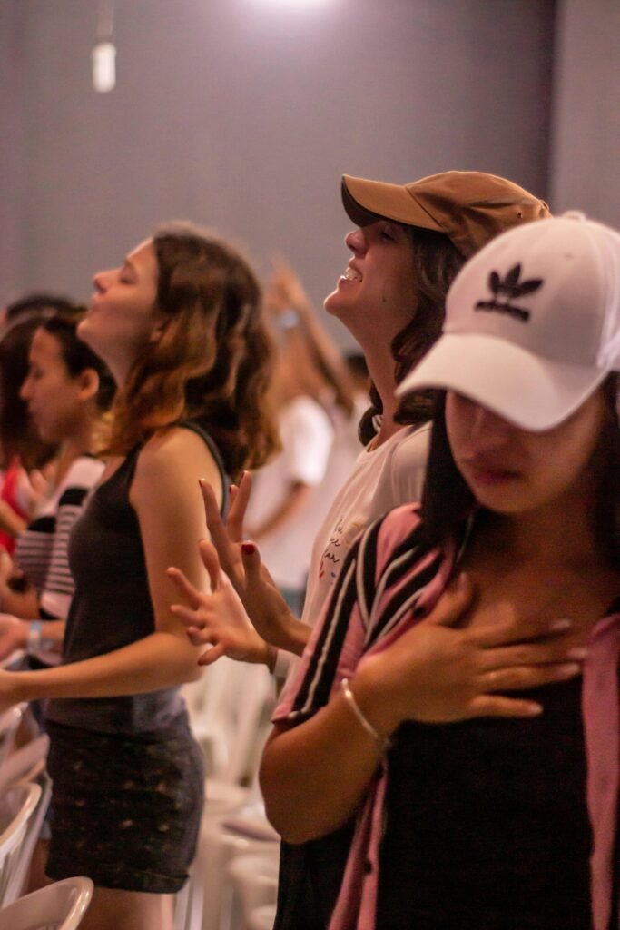 A group of diverse young women engaging deeply in a worship session, showing expressions of devotion and focus.