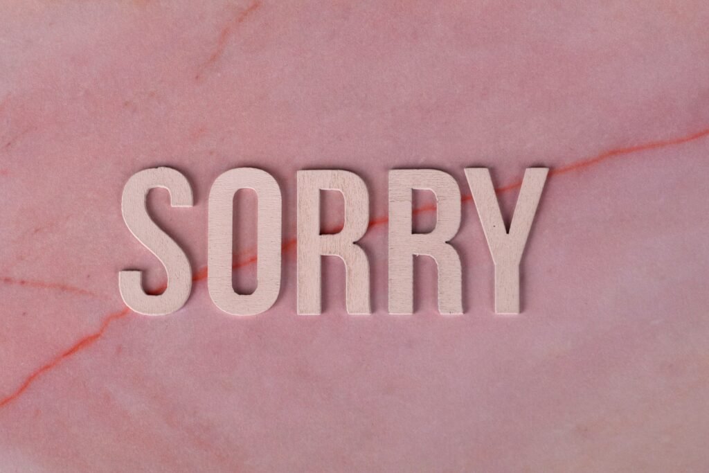 Wooden letters spelling 'SORRY' on a pink marble surface, apology concept.